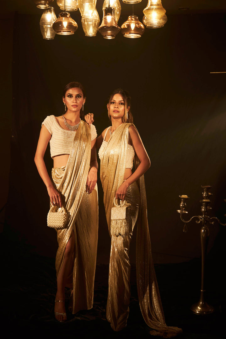 Saia metallic slit saree with an embellished pearl blouse will definitely make you look sassy and elegant in an event.  Tailored to perfection in a metallic fabric, the saree features a slit from the waist level and has an attached palla which creates a great fall.  It comes with a pearl embellished blouse with cap sleeves and deep from the back.